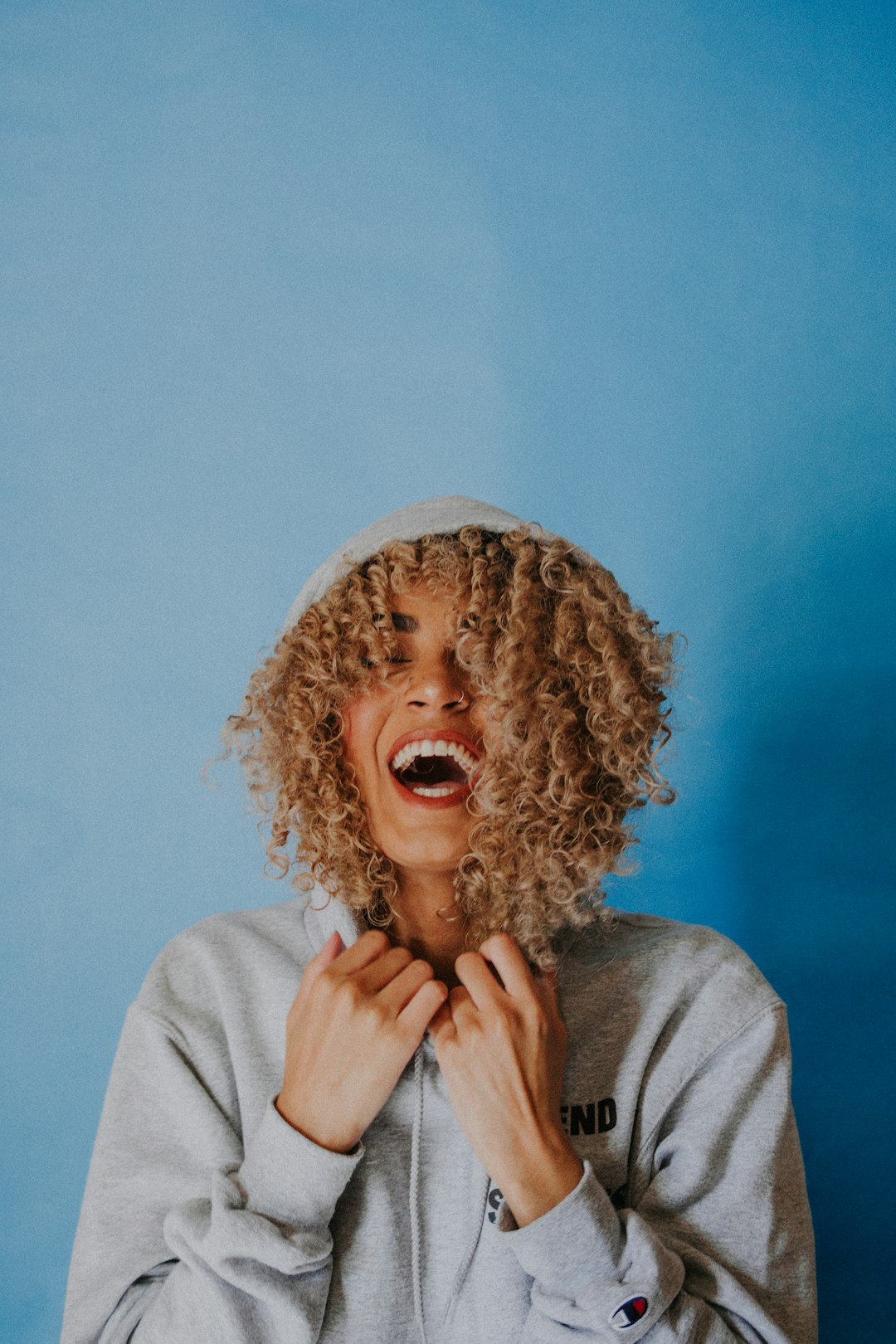 Nadhia doing what she enjoys most - laughing. by Teacher Supply Store smiling woman wearing gray hoodie